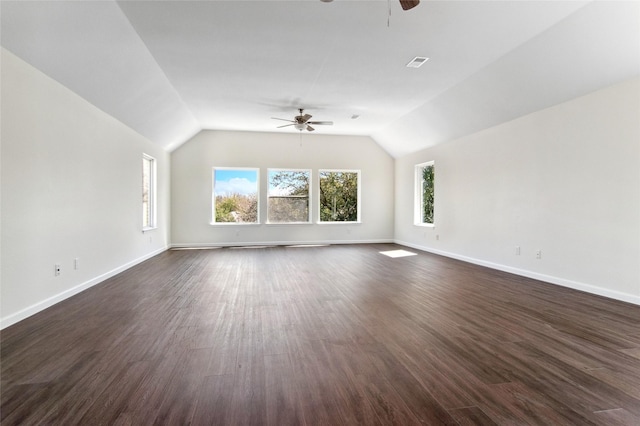 interior space featuring dark wood-style floors, visible vents, a ceiling fan, vaulted ceiling, and baseboards