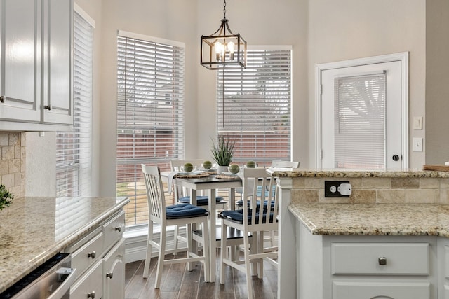 kitchen with hanging light fixtures, backsplash, white cabinetry, wood finished floors, and dishwasher