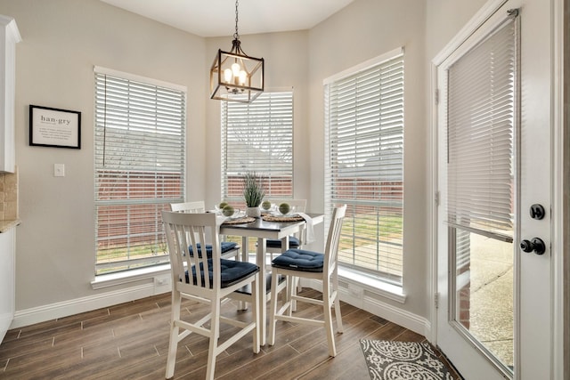 dining space featuring baseboards, wood finished floors, and an inviting chandelier