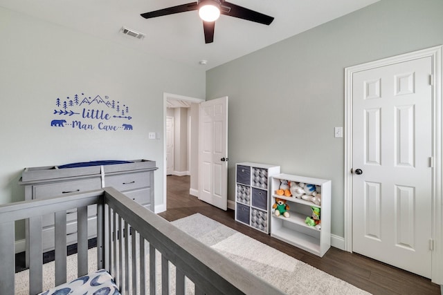 bedroom with baseboards, visible vents, a ceiling fan, wood finished floors, and a nursery area