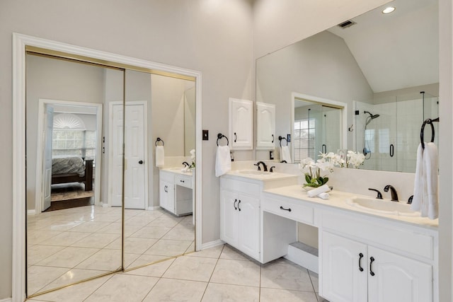 ensuite bathroom with a stall shower, vaulted ceiling, a sink, and tile patterned floors