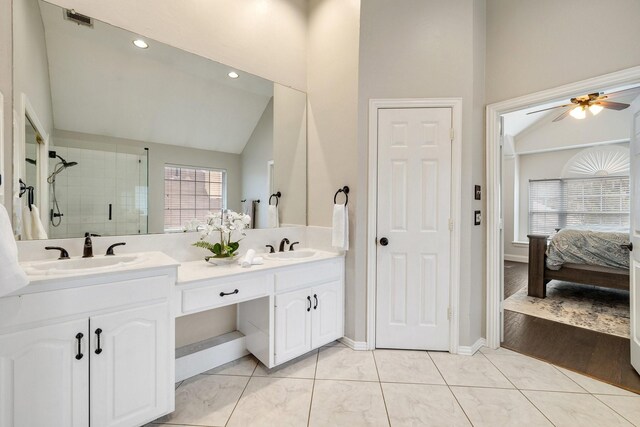 bathroom featuring lofted ceiling, double vanity, a stall shower, and a sink