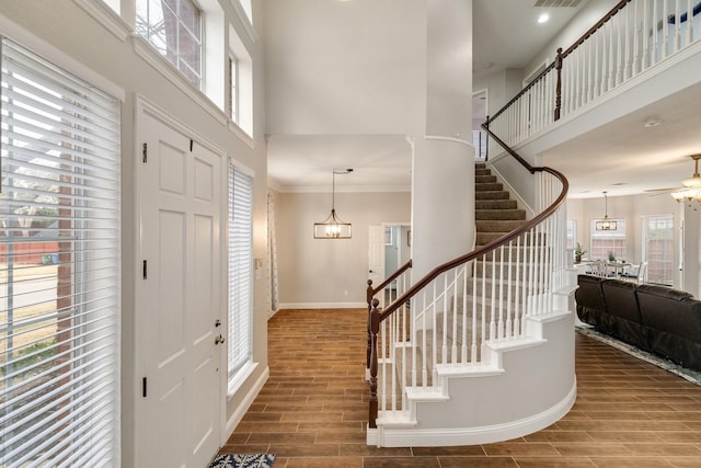 entryway featuring visible vents, stairway, a towering ceiling, wood tiled floor, and baseboards