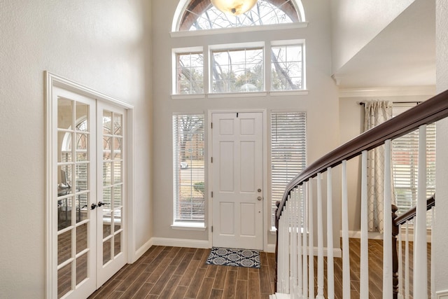 foyer entrance with a high ceiling, wood finish floors, baseboards, stairs, and french doors