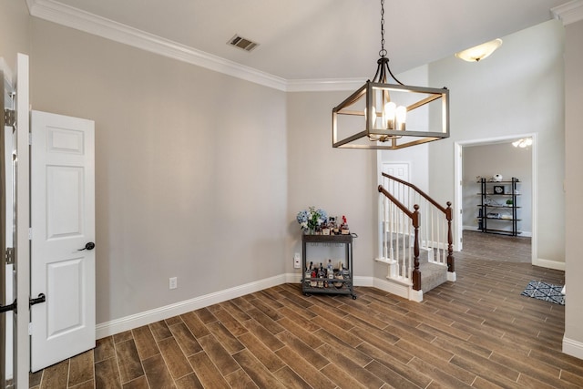 empty room with crown molding, a notable chandelier, visible vents, wood tiled floor, and stairs