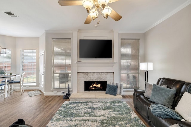 living room with visible vents, crown molding, a fireplace, and wood finished floors