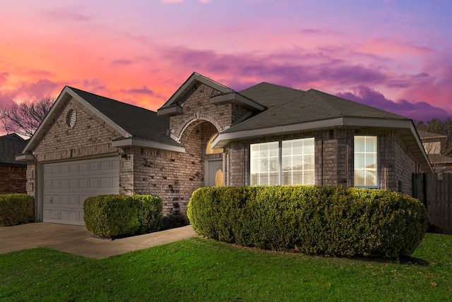 single story home featuring a garage, concrete driveway, brick siding, and a lawn