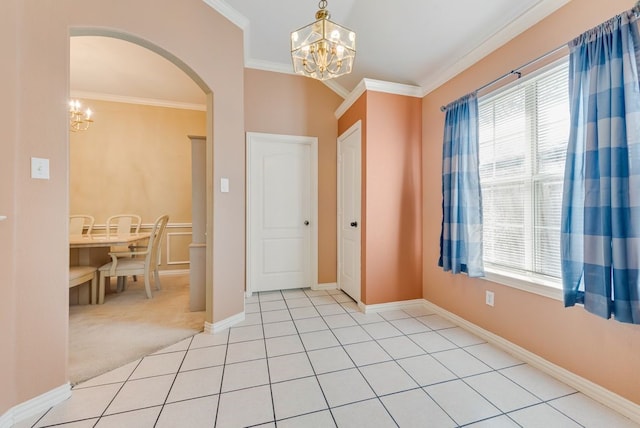 foyer with light tile patterned floors, arched walkways, light colored carpet, crown molding, and a chandelier