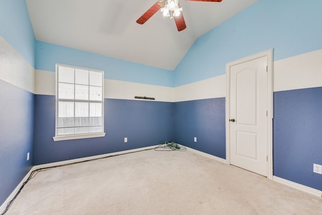 carpeted spare room featuring lofted ceiling, baseboards, and a ceiling fan