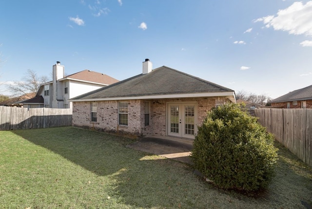 back of house with french doors, brick siding, a yard, and a fenced backyard