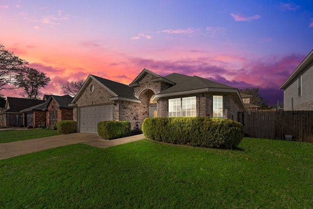 view of front of home with driveway, a yard, fence, and brick siding