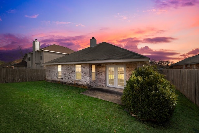 back of house featuring a yard, french doors, a fenced backyard, and brick siding