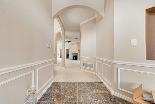 hallway with visible vents, arched walkways, a decorative wall, and wainscoting