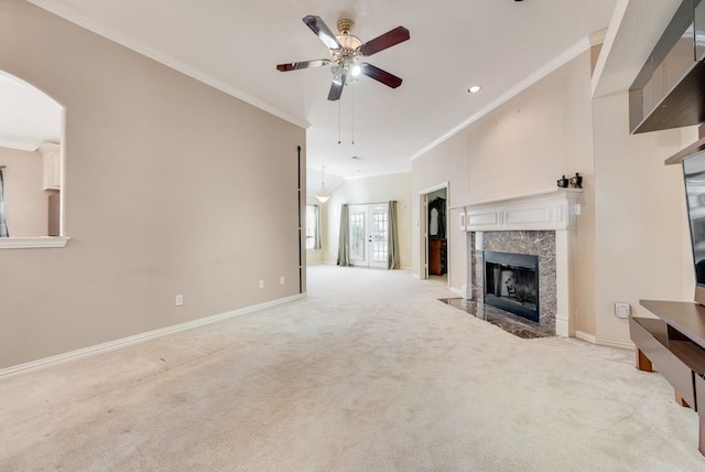 unfurnished living room with carpet floors, ornamental molding, a high end fireplace, a ceiling fan, and baseboards