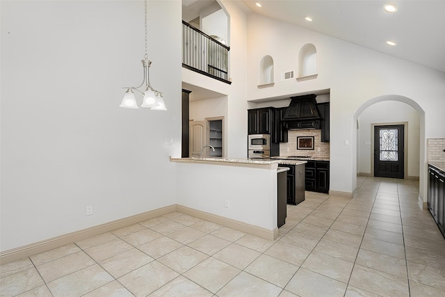 kitchen with premium range hood, visible vents, backsplash, dark cabinetry, and stainless steel appliances