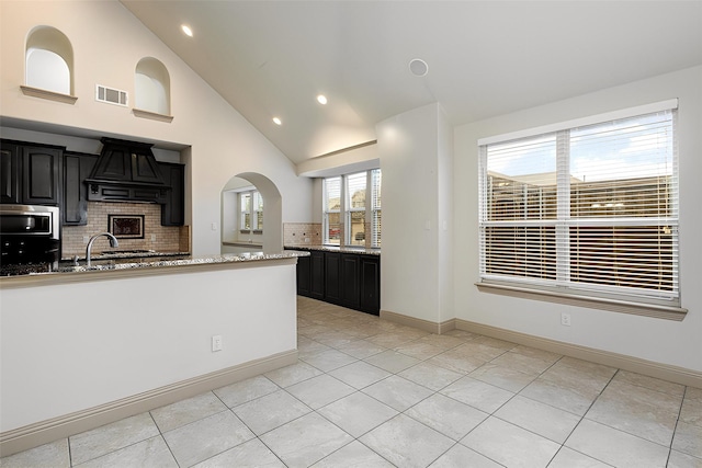 kitchen featuring stainless steel microwave, visible vents, dark cabinets, and custom range hood