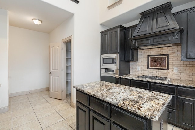 kitchen with decorative backsplash, dark cabinets, appliances with stainless steel finishes, and premium range hood