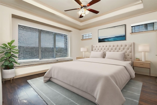 bedroom featuring ceiling fan, a raised ceiling, wood finished floors, and ornamental molding