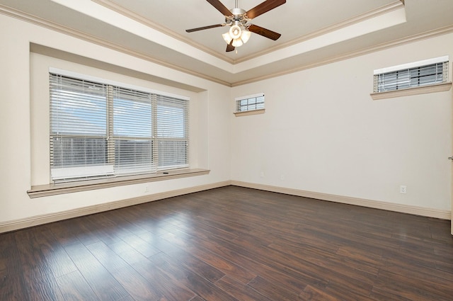 unfurnished room with ornamental molding, a raised ceiling, baseboards, and dark wood-style flooring