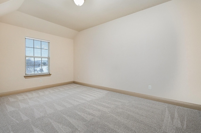 empty room featuring vaulted ceiling, baseboards, and light carpet