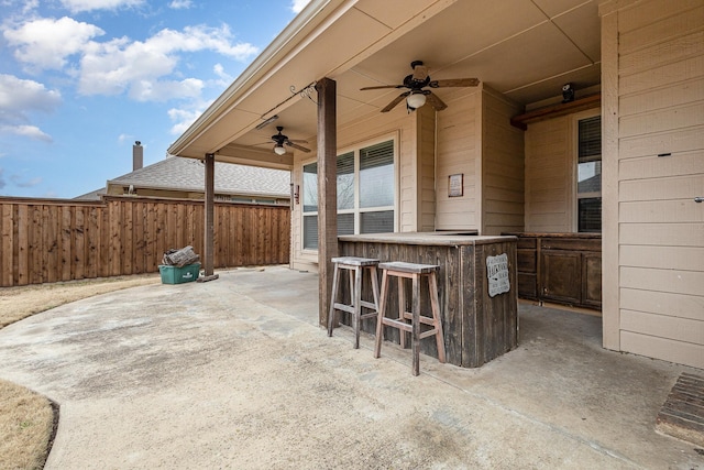 view of patio / terrace featuring a ceiling fan, fence, and outdoor dry bar