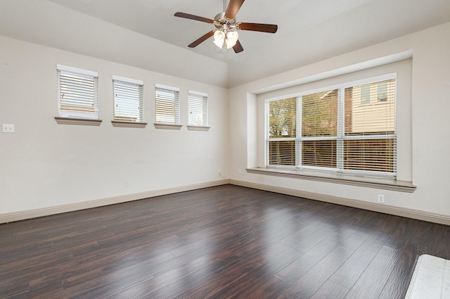 spare room featuring dark wood finished floors, vaulted ceiling, baseboards, and ceiling fan