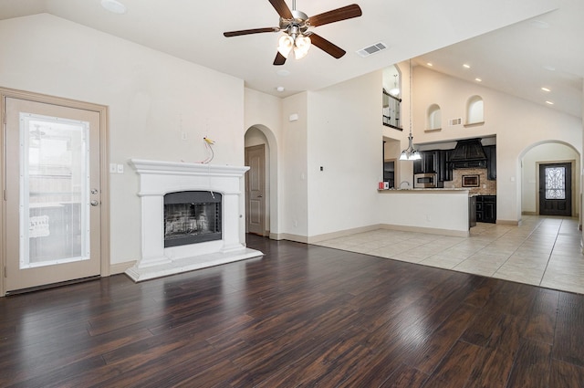 unfurnished living room featuring visible vents, a fireplace with raised hearth, a ceiling fan, and light wood finished floors