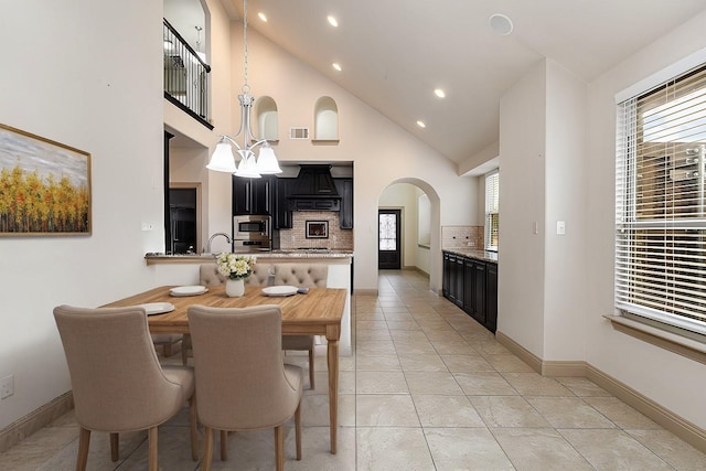 dining room featuring visible vents, baseboards, a chandelier, light tile patterned floors, and arched walkways