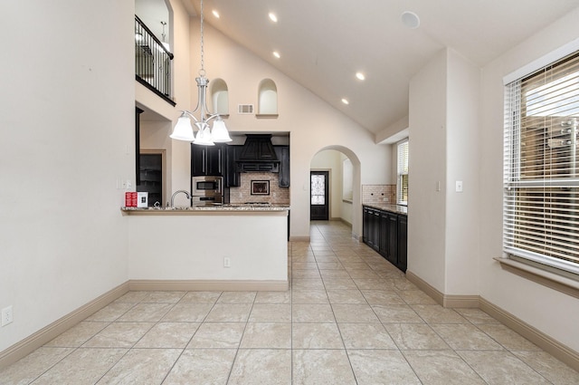 kitchen featuring dark cabinetry, visible vents, appliances with stainless steel finishes, tasteful backsplash, and a chandelier