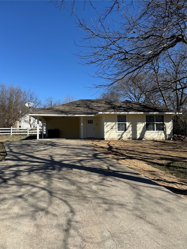 exterior space with a shingled roof, driveway, and fence