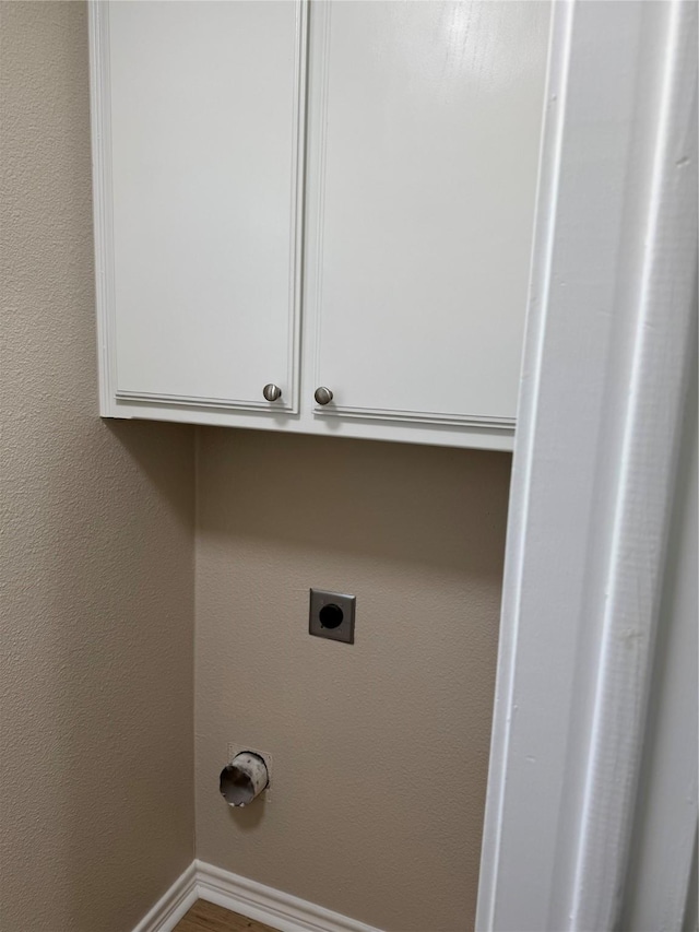 laundry room with baseboards, a textured wall, cabinet space, and hookup for an electric dryer