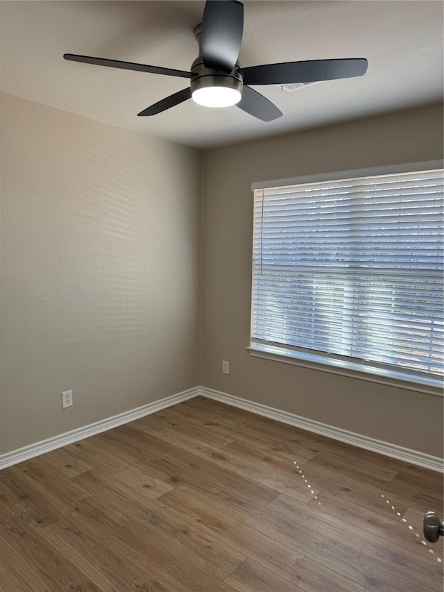 unfurnished room featuring a ceiling fan, baseboards, and wood finished floors