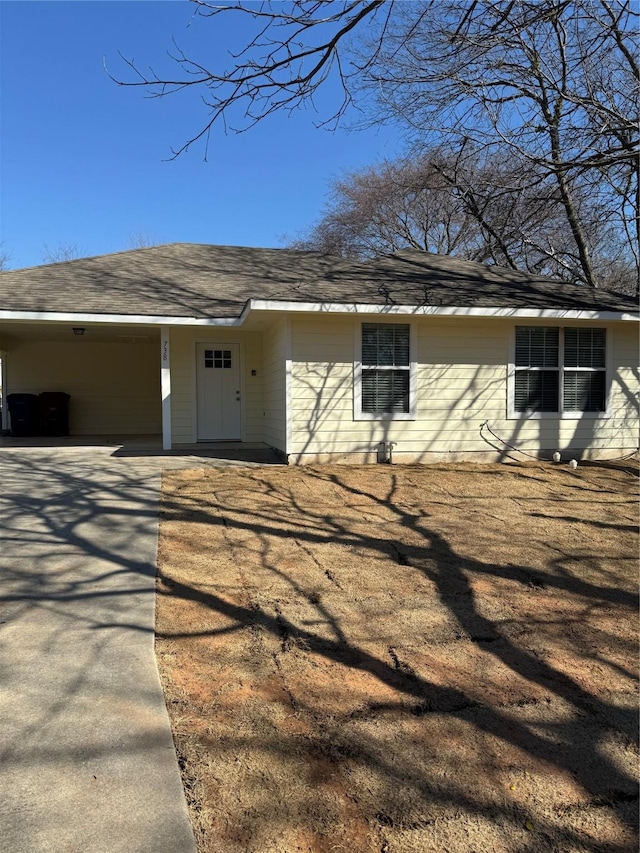 view of home's exterior featuring a carport, roof with shingles, and driveway