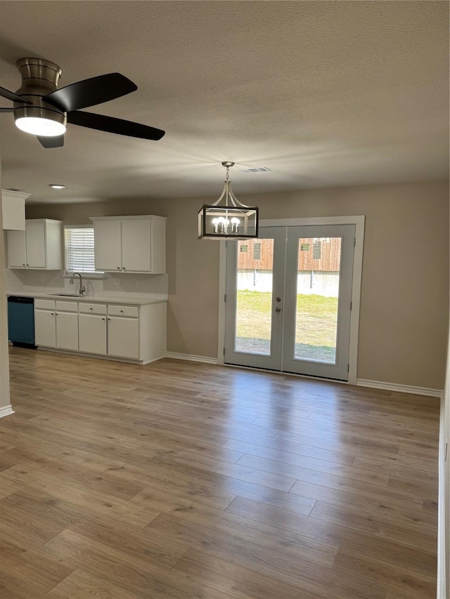 interior space featuring white cabinets, dishwasher, light wood-style flooring, light countertops, and a textured ceiling