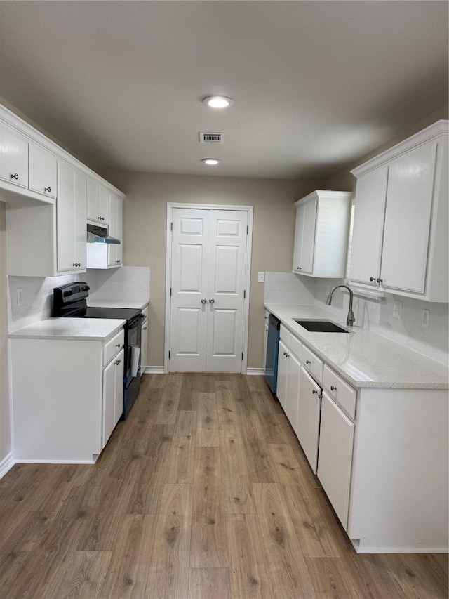 kitchen with dishwashing machine, under cabinet range hood, electric range, a sink, and visible vents