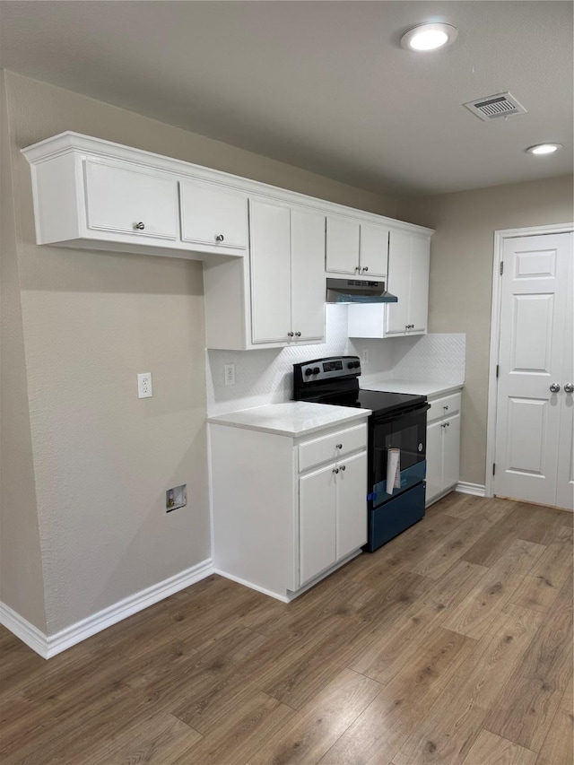 kitchen with black electric range, visible vents, light wood-style flooring, white cabinetry, and under cabinet range hood