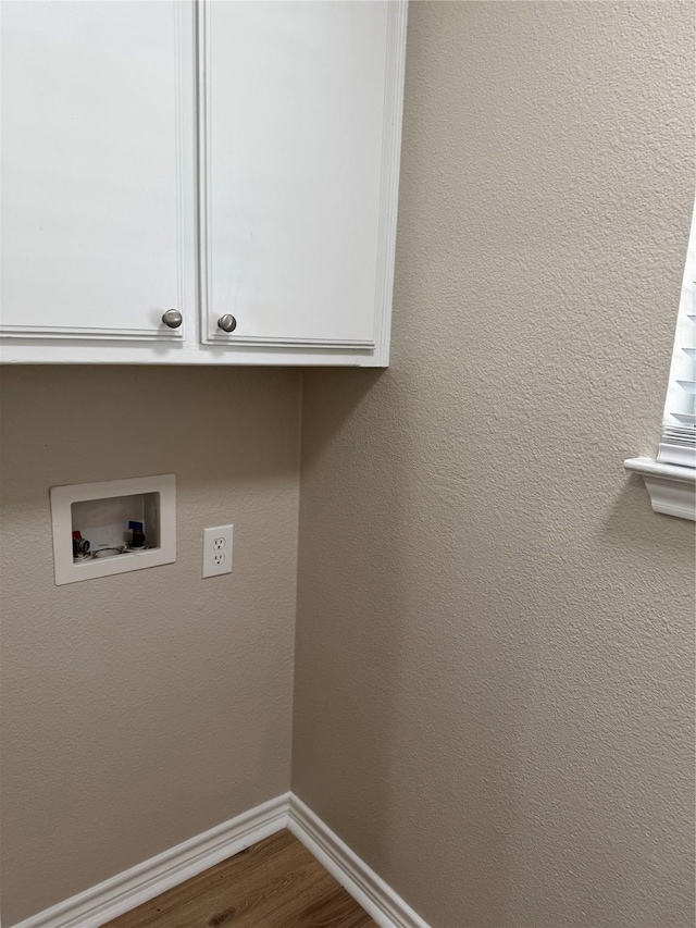 clothes washing area featuring cabinet space, baseboards, a textured wall, dark wood-style flooring, and washer hookup