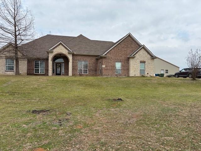 view of front of property with brick siding, roof with shingles, and a front yard