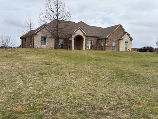 french country inspired facade with a front lawn and brick siding