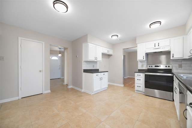 kitchen featuring dark countertops, decorative backsplash, appliances with stainless steel finishes, white cabinets, and under cabinet range hood