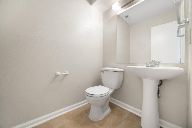 half bathroom featuring toilet, visible vents, baseboards, and tile patterned floors