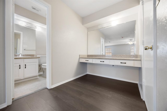 half bathroom with visible vents, baseboards, toilet, wood finished floors, and vanity