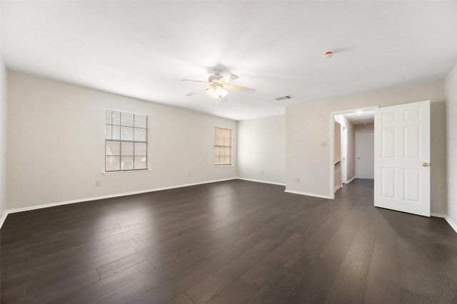 unfurnished room with ceiling fan, visible vents, dark wood finished floors, and baseboards