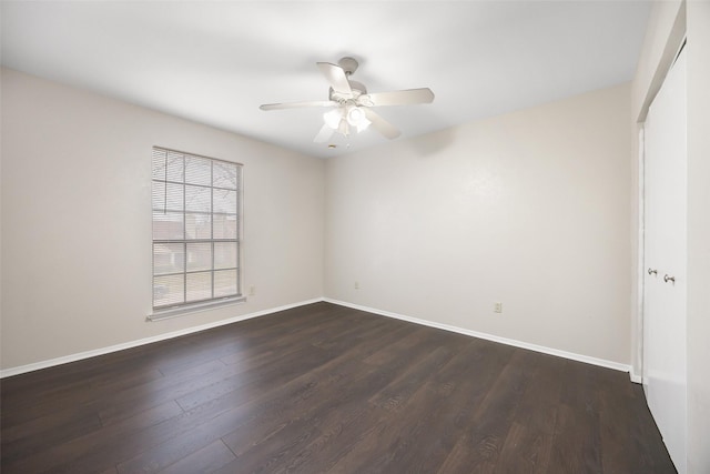 spare room featuring dark wood-style flooring, ceiling fan, and baseboards