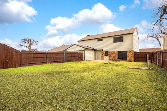 back of property with a fenced backyard, a lawn, and brick siding