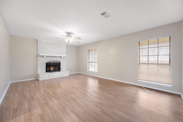 unfurnished living room featuring light wood-style floors, ceiling fan, a fireplace, and visible vents