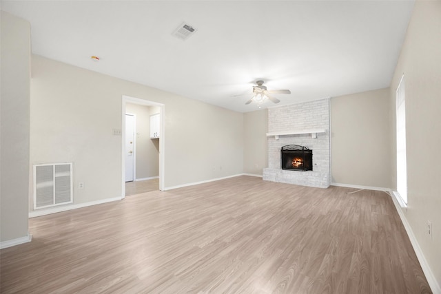 unfurnished living room with visible vents, baseboards, ceiling fan, light wood-style flooring, and a fireplace