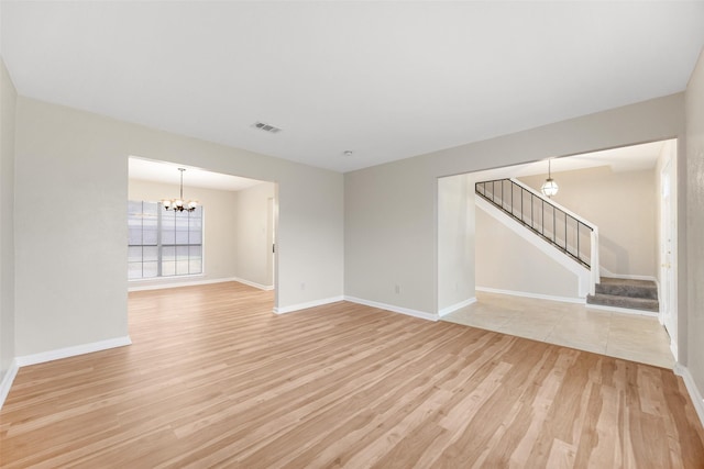 unfurnished room with a notable chandelier, visible vents, stairway, light wood-type flooring, and baseboards