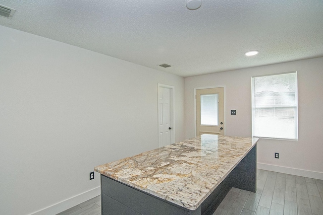 kitchen featuring light wood-style floors, baseboards, a kitchen island, and visible vents