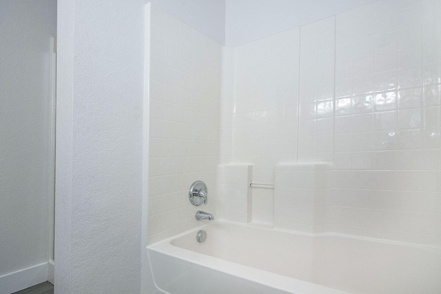 bathroom featuring a textured wall and tub / shower combination